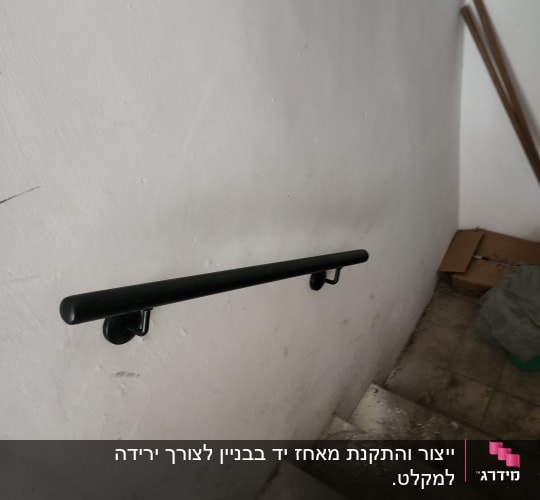 מעקה שחור מותקן על קיר מדרגות